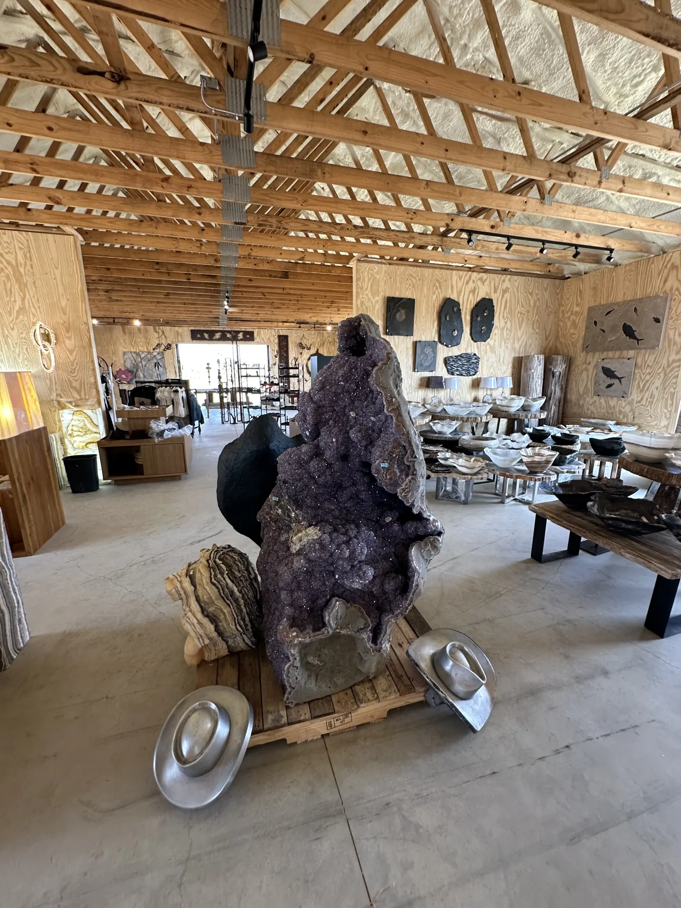 Giant amethyst geode surrounded by stone bowls and hats at The Hive