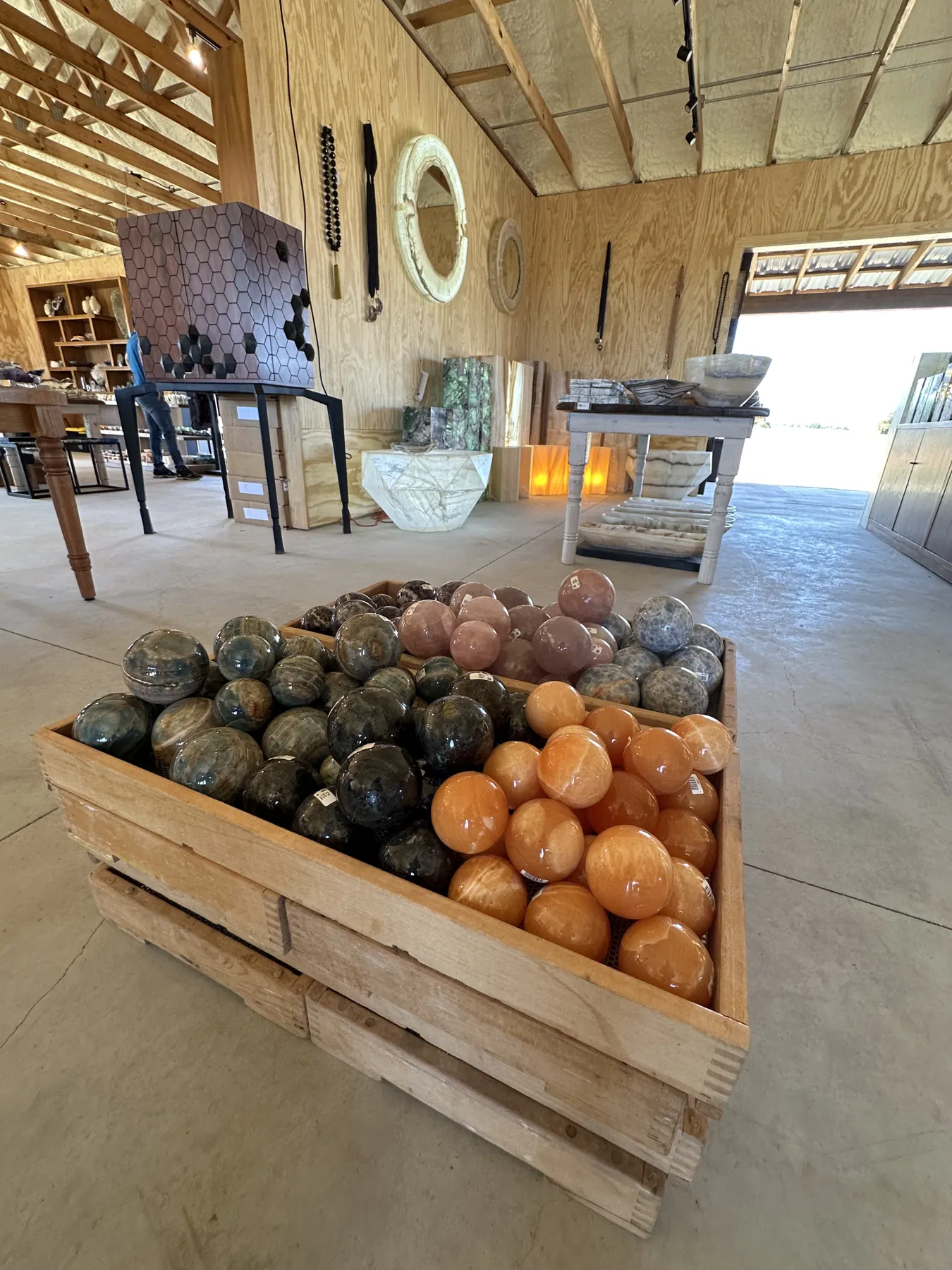Crates of polished stone spheres in earthy colors inside The Hive