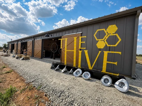 The Hive facade and illuminated yellow sign under a blue Texas sky